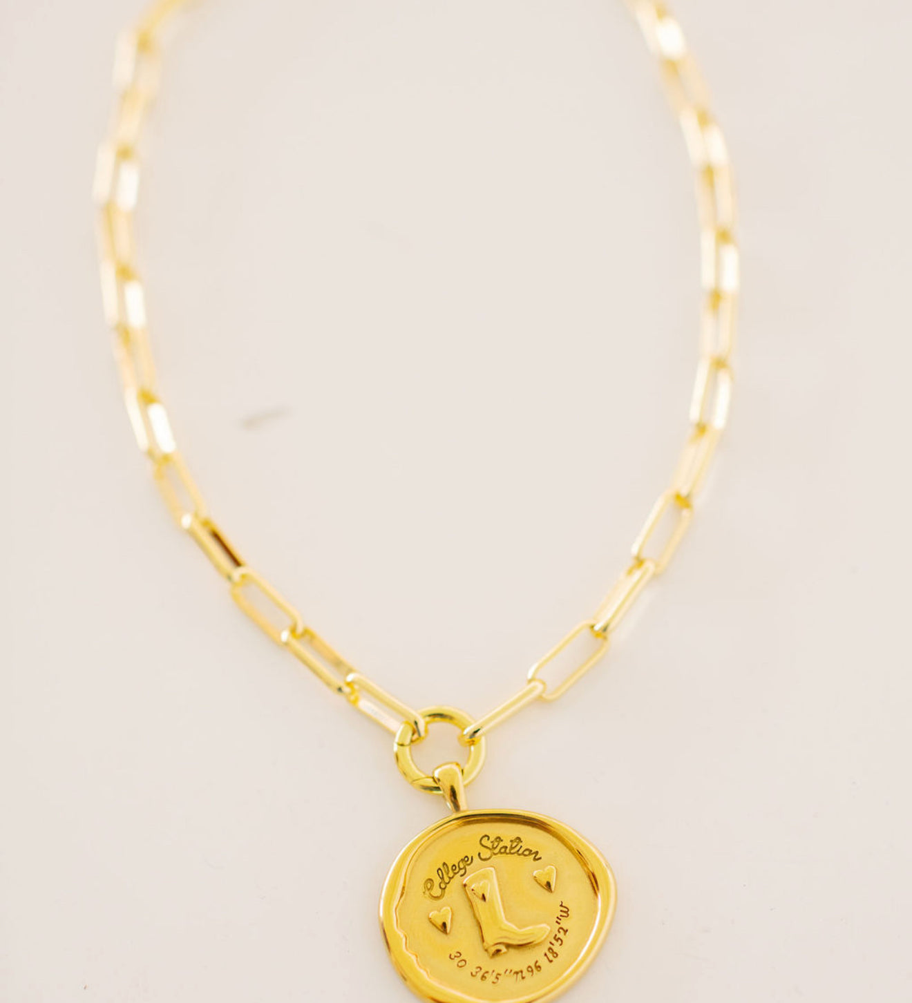 College Station Necklace, gold medallion with a cowgirl boot, two hearts and city coordinates on a paperclip chain