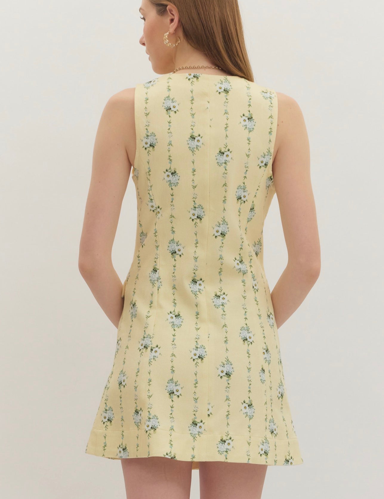 Back view of the Lemon Yellow Floral Dress, a pastel yellow dress with blue floral sprigs