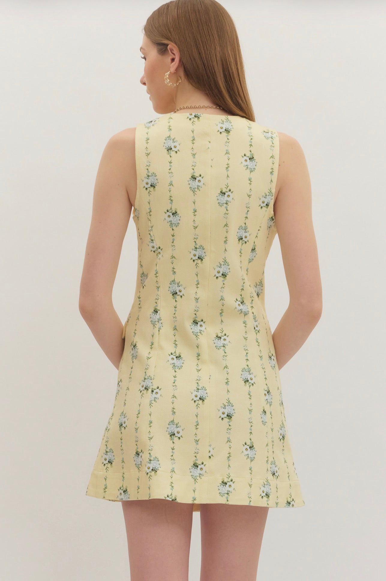 Back view of the Lemon Yellow Floral Dress, a pastel yellow dress with blue floral sprigs